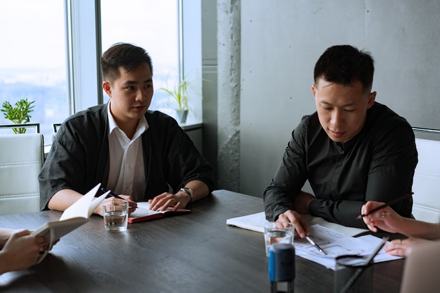 dua orang asia sedang berdiskusi dengan anggota tim