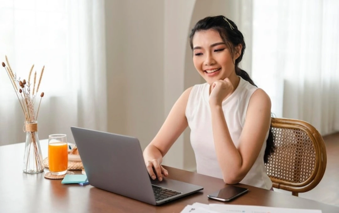 wanita asia tersenyum di depan laptop